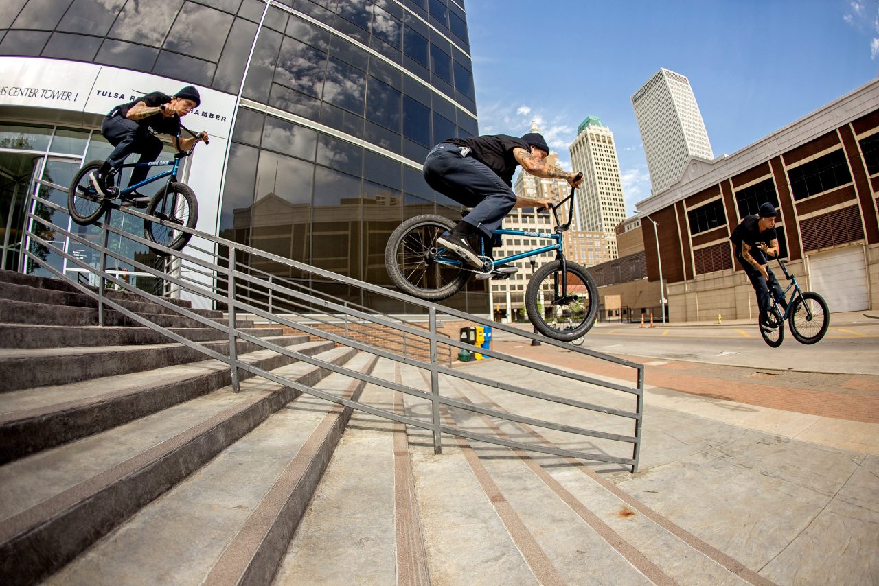 A rider on a Kink BMX jumping a handrail down a flight of city steps, shown in three stages